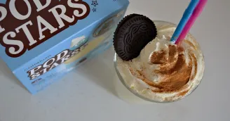 Podstars kakaíčka modrá krabička vedle sklenice se šlehačkou posypanou kakaem Oreo na vrcholu dvě barevné brčky