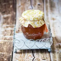 Bylinný sirup skleněná dóza s látkovým víčkem na kovovém stojánku se srdíčky na dřevěném stole