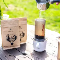 dvě hnědé kraftové balení kávy s nápisem ECUADOR na dřevěném stole