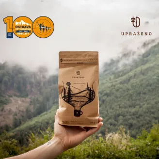 Ostrava city marathon logo a UPRÁŽENO logo na balení kávy držené rukou v přírodě