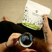 balení kávy bílé obal s grafikou krajiny a zrnky kávy logo na obalu