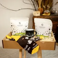 dárkový balíček dva bílé sáčky s logem UPRAZENO černý hrnek kartonové balení se slámou žluté černé ponožky