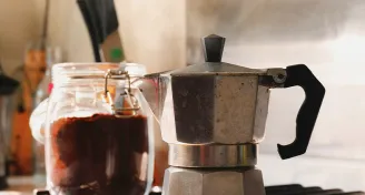 moka konvička a sklenice s mletou kávou na kuchyňské lince